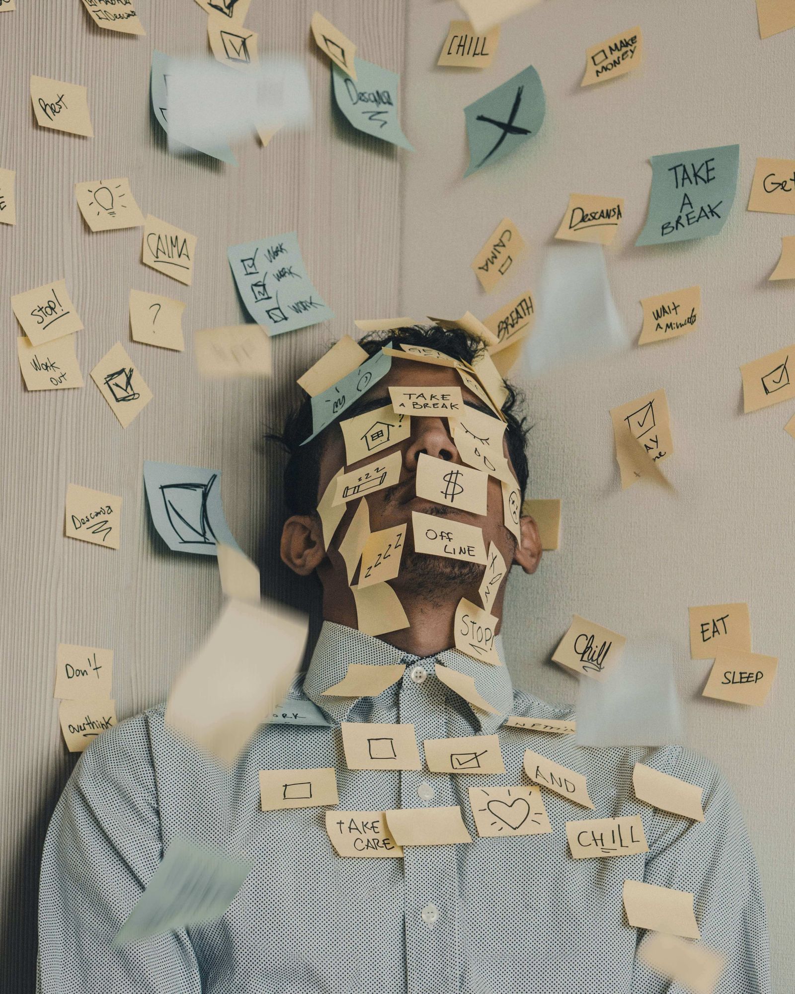 Man lying down, with many post it notes on face, overwhelmed